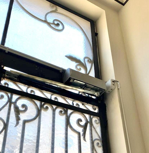 Moteur à bras articulés installé sur un portail battant
