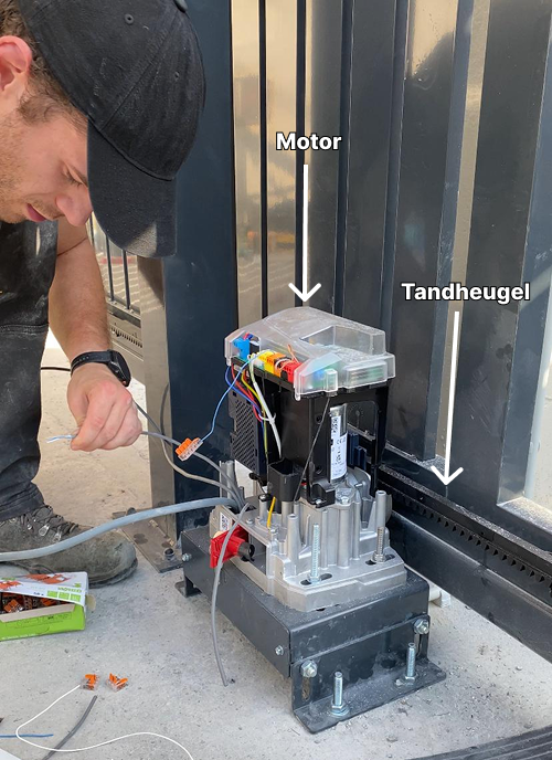 Teamlid van Open-It voert de bekabeling uit van een motor voor een schuifpoort
